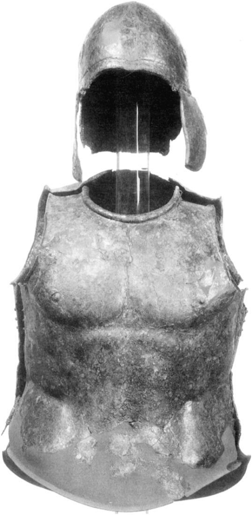 Ελληνιστικός (τέλη 4ου π.Χ αιώνα) ανατομικός μυώδης θώρακας με ανοικτό κράνος Αττικού τύπου, τα οποία εκτίθενται στο Μουσείο Getty (ΗΠΑ). Το πάχος του θώρακα είναι 0.535 m και του κράνους 0.225 m , ενώ δεν είναι καταγεγραμμένο το σημείο το οποίο έχει βρεθεί. Πηγή φωτογραφίας: Emeline Hill Richardson, The Muscle Cuirass in Etruria and Southern Italy: Votive Bronzes, American Journal of Archaeology, Vol. 100, No. 1 (Jan., 1996), p93. Image may be copyrighted.